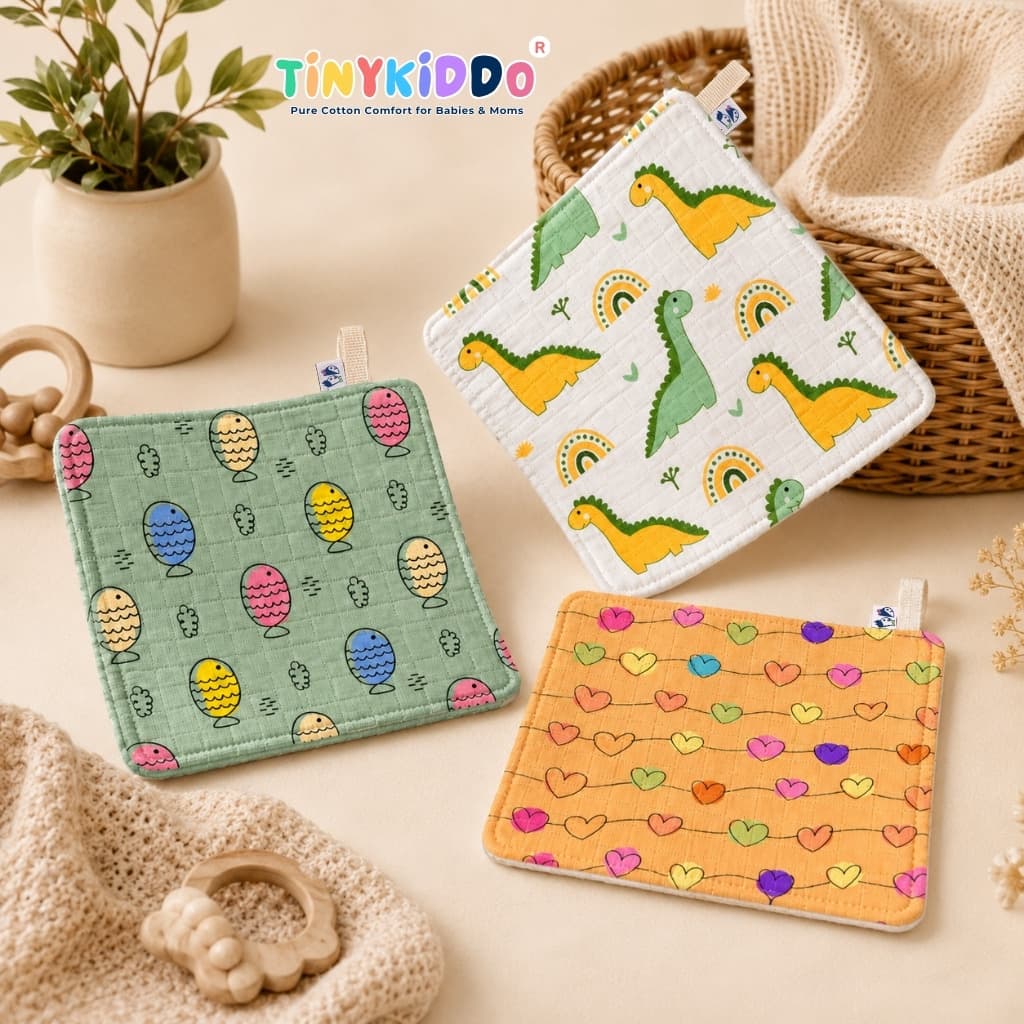Three folded muslin washcloths in dinosaur, egg and heart prints