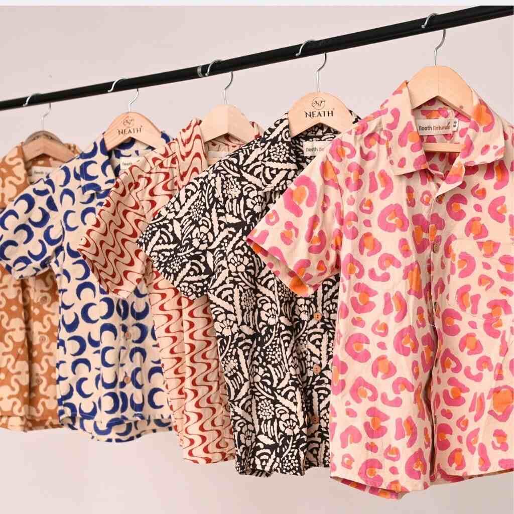 Hand block printed shirts on a rail in indigo, black and coral prints