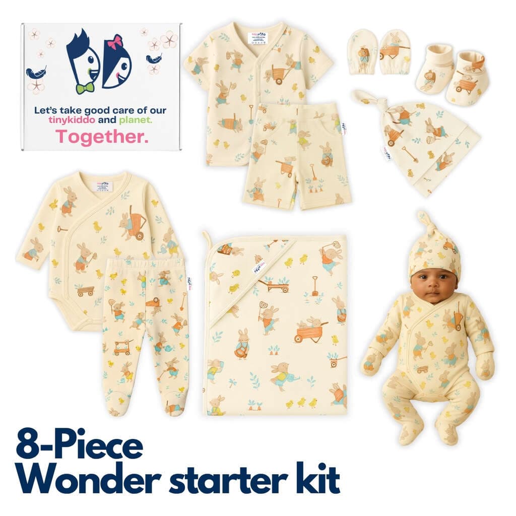 All eight pieces of the newborn starter kit laid out in cream cotton with a woodland animal print