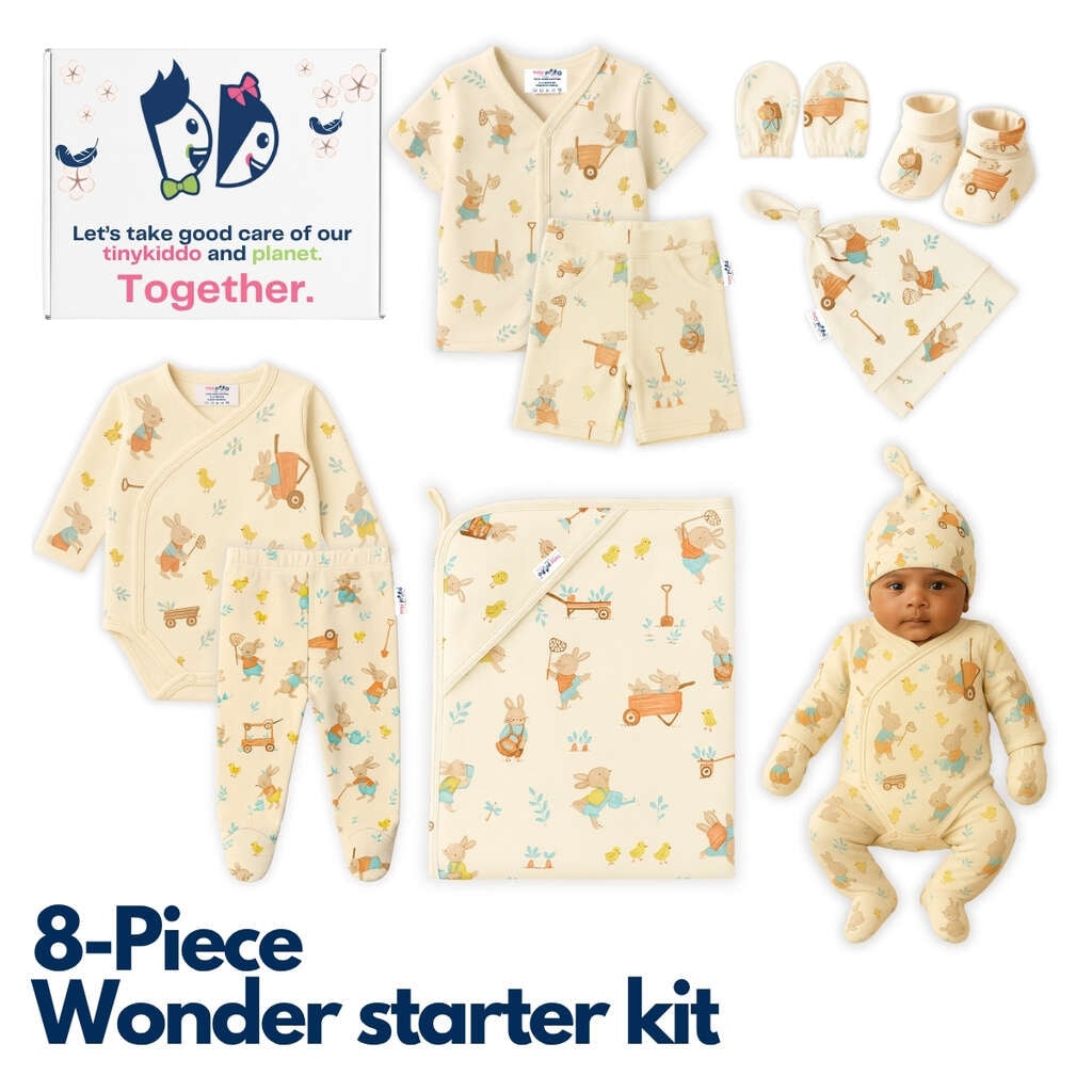 All eight pieces of the newborn starter kit laid out in cream cotton with a woodland animal print